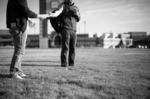 man passing out Christian tracts in front of a stadium at a college