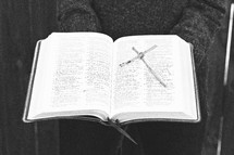 a woman holding a Bible and a cross made of sticks 
