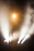 Stage lights shine through the fog.