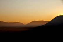 Distant hills with sunrise sky and misty mountains