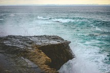 waves crashing into rocks along a shore 