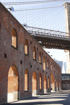 side of brick building with arches - under bridge