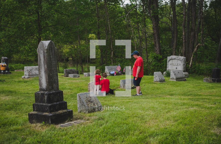 children visiting a cemetery with their father 