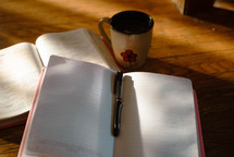open notebook, open Bible, pen, and coffee 