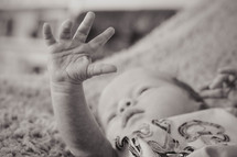 Newborn baby boy staring at his hand.