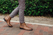 man in boots walking on a brick sidewalk 