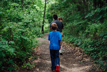 father and kids walking on a path in the woods 