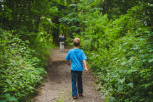 father and kids walking on a path in the woods 
