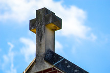stone cross topper on a church roof 