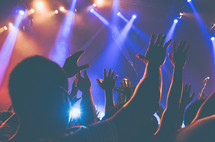 audience with hands raised at a concert 