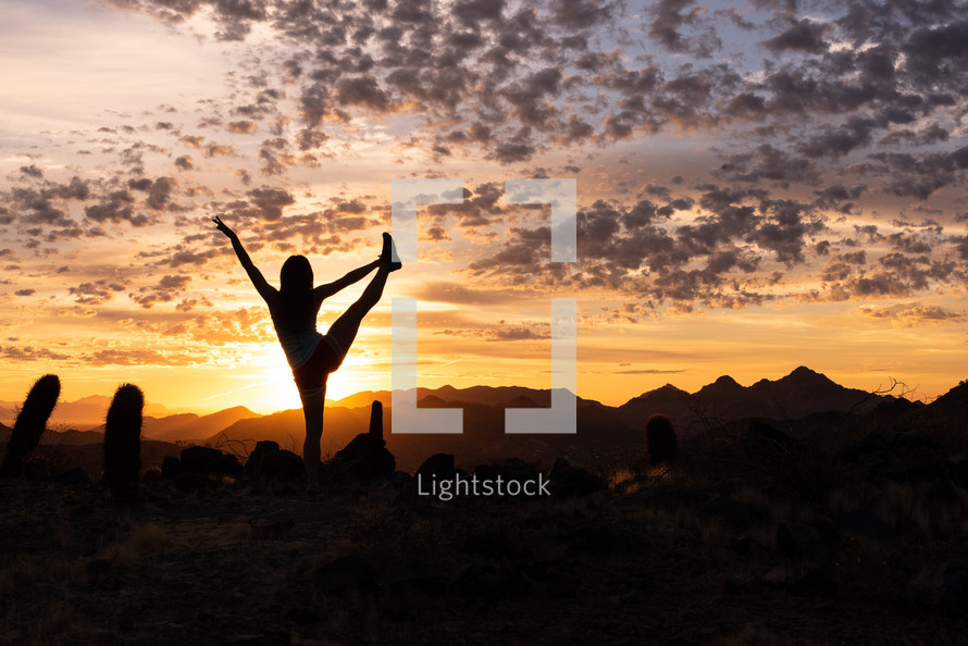 silhouette of a girl stretching in a desert at sunset 