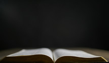Open bible on a table with dark background