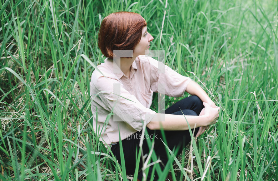 a woman sitting in tall grasses 