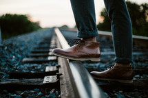 boots standing on railroad tracks 