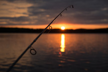 fishing pole over water at sunset 