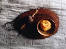 yarn wrapped around a stick and peonies in a wood bowl 
