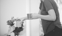 a woman handing a mug to her friends 