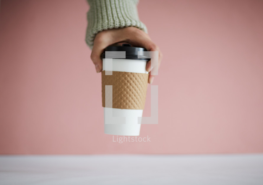 a hand taking a coffee cup 