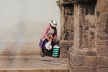 a woman gathering her bags on a stone walkway 