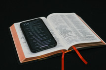Bible app on a cellphone on the pages of a Bible 