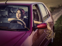 a woman driving a car holding picked flowers 