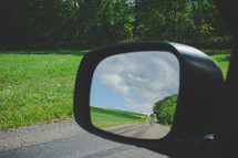 view of a rural road in the rearview mirror 