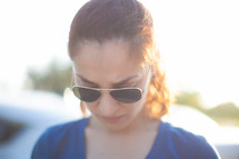 Woman in sunglasses praying outside.