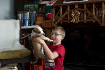 a boy holding up a puppy 