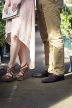 Legs and feet of a man and woman standing together.