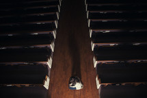 A woman kneeling in the aisle of a church 