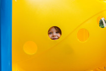 face of a child looking through playground equipment 