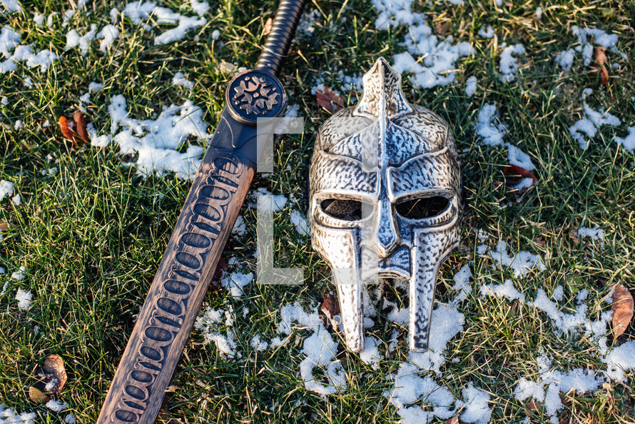 mask and sword in the grass in the snow 