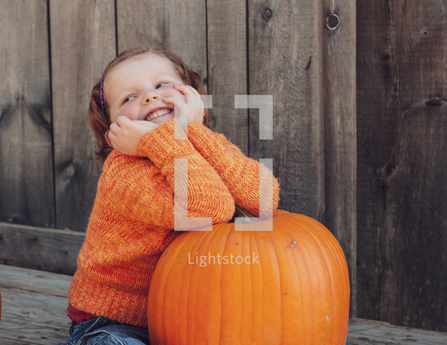 smiling child on an orange pumpkin 