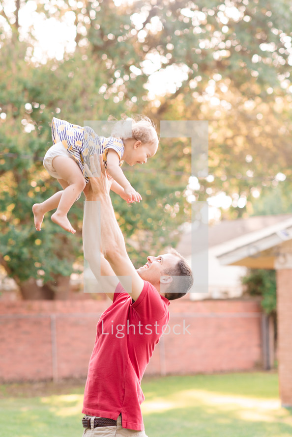 father tossing his daughter in the air 