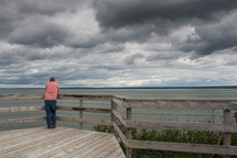 man standing on a deck looking out at water 