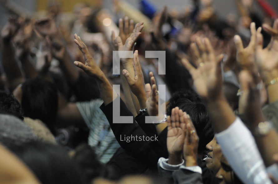 Congregation with hands raised praising God during worship service.