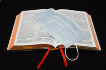 surgical mask on the pages of a Bible 