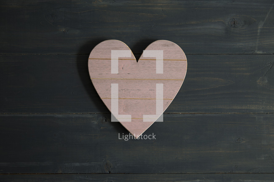 A pink heart of wood on dark wood.