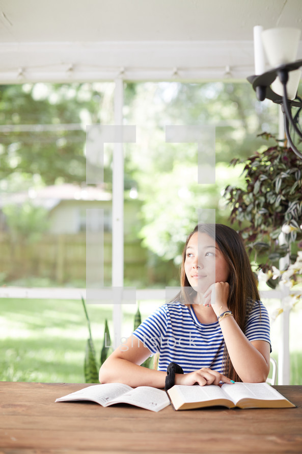 a young woman reading a Bible on her porch 