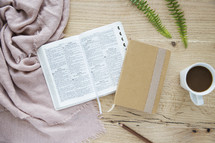 open Bible, coffee, mug, and journal on a table 