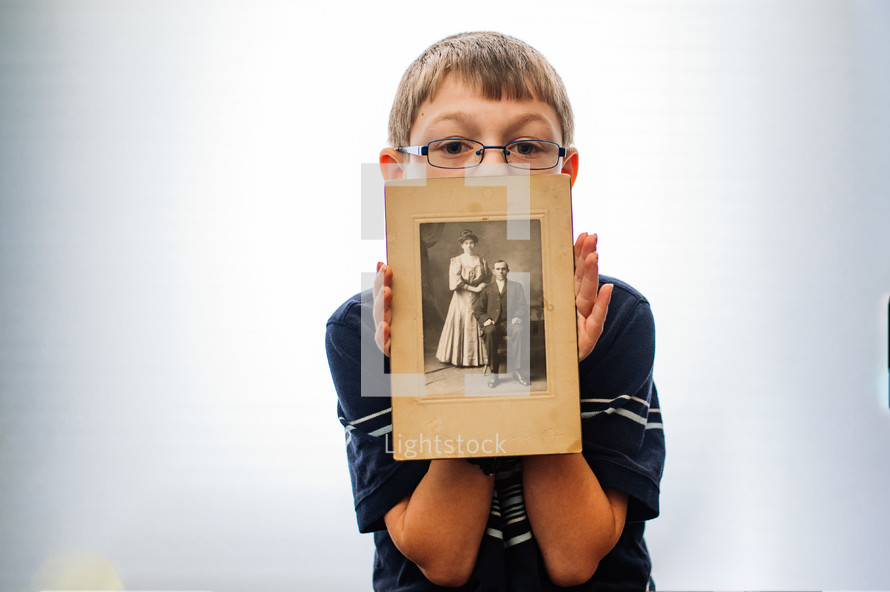 a boy holding an old photograph of his ancestors 