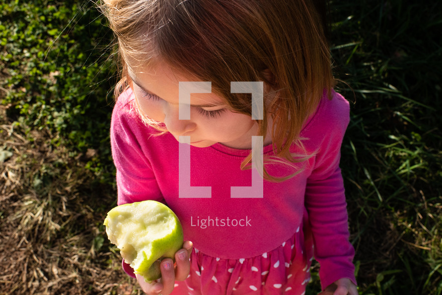 Little girl eating a green apple