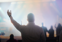 a man at a worship service with hand raised 