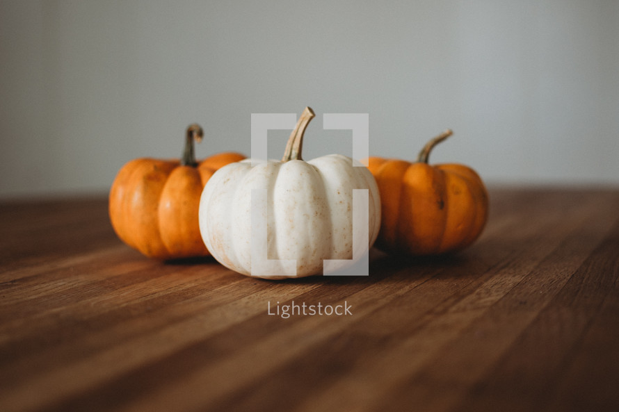 orange and white pumpkins on a wood table 