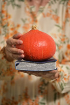 a woman holding a Bible and a pumpkin 