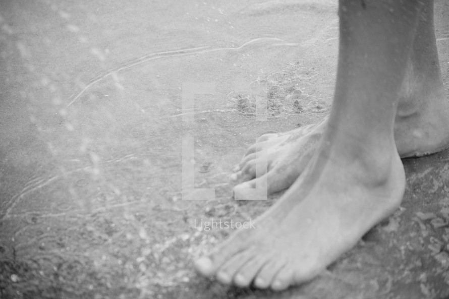 child washing sand off his feet 