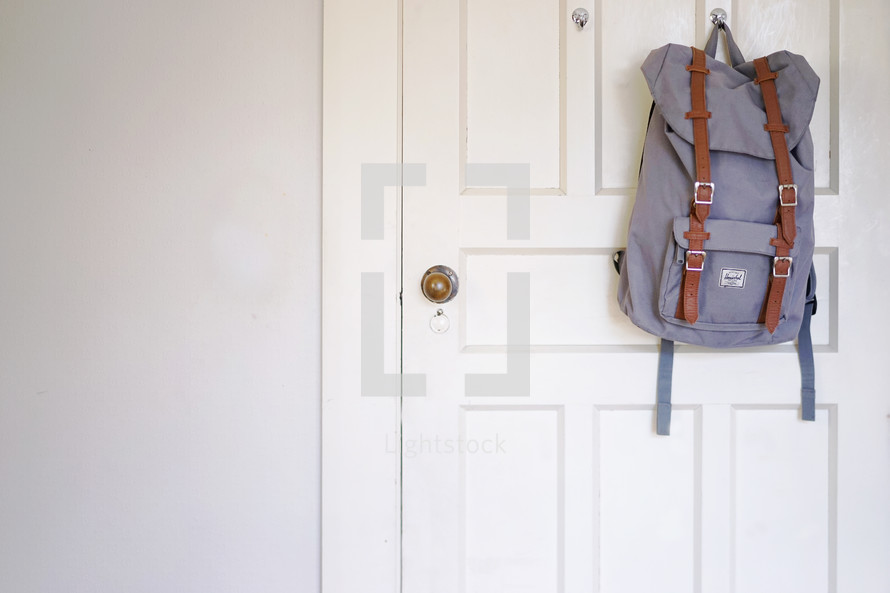book bag hanging on the back of a door 