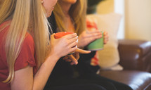 women sitting on a couch drinking coffee 