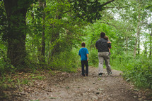 a father walking with his children on a path through the woods 