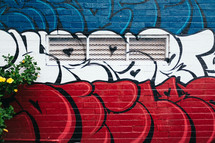 red, white, and blue graffiti on a wall 